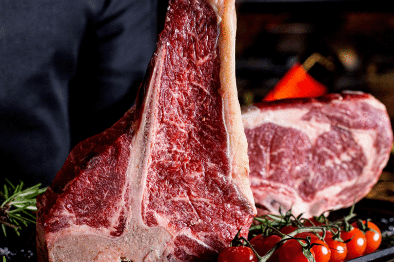 Imagem de um corte de carne bovina, com textura suculenta e marmorizada, preparado para churrasco, decorado com tomates cereja e ramos de alecrim.