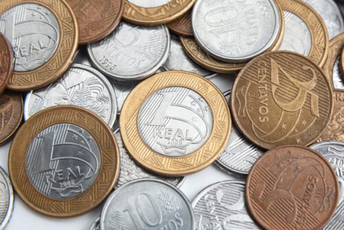 Fundo com várias moedas de euro em diferentes valores e cores, incluindo moedas de 1, 2, 5, 10 e 20 centavos, mostrando detalhes de suas faces.