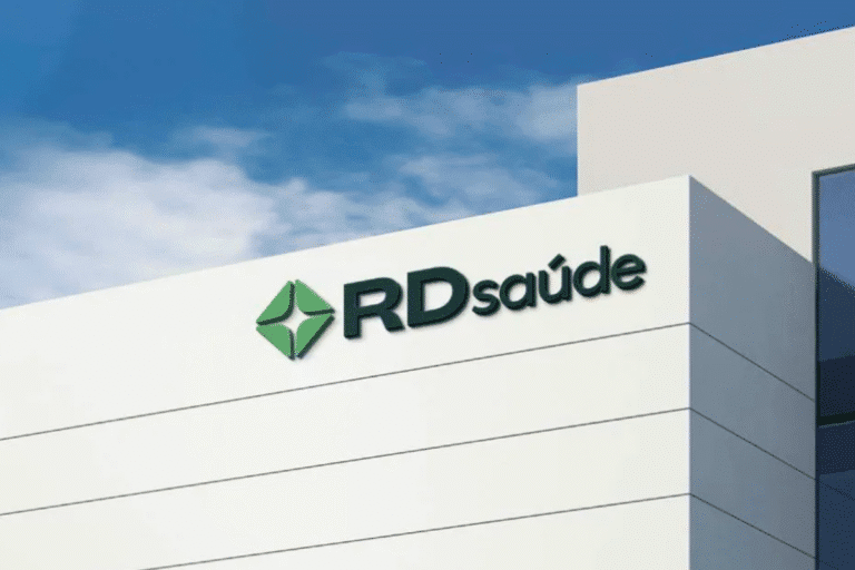 Imagem de um edifício moderno com o logo da RD Saúde, uma clínica ou centro de saúde, sob um céu azul com algumas nuvens, destacando-se na arquitetura branca.