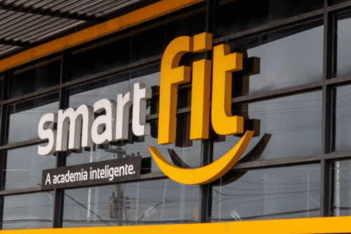 Fachada de uma academia inteligente chamada smart fit com o slogan A academia inteligente, destacando o ambiente de ginástica moderna e acessível.
