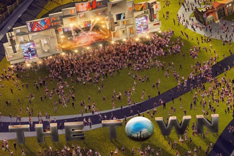 Impressionante vista de uma grande apresentação ao ar livre na arena de The Town, com muitas pessoas assistindo a show e iluminação vibrante.