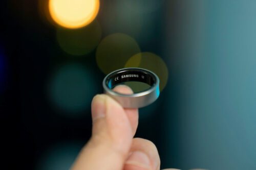 Pessoa segurando um anel inteligente Samsung em destaque, mostrando o design moderno e tecnológico do wearable.