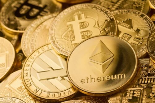 Moedas físicas representando criptomoedas como Bitcoin, Ethereum e Litecoin em fundo dourado.