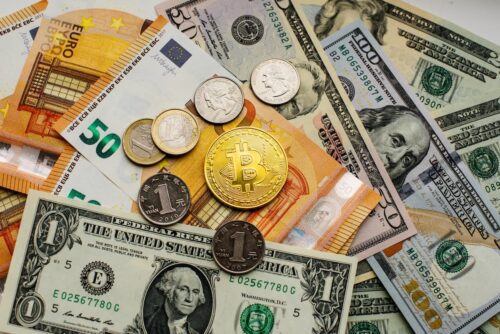 Fintechs e soluções em Stablecoins ilustradas com moedas tradicionais, bitcoin e cédulas em diferentes moedas.