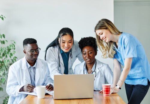 Equipe médica diversa analisando informações em um laptop, representando inovação e tecnologia na saúde.