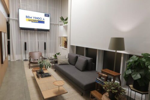 Sala moderna com TV exibindo NR Sports, Neymar e Rota DUE Caribe Brasileiro, decoração clean e plantas.