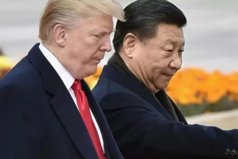 Donald Trump e Xi Jinping caminhando lado a lado, com flores ao fundo, durante um encontro diplomático.
