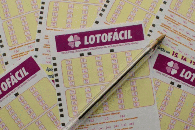 Uma caneta repousa sobre vários bilhetes de loteria "Lotofácil" com grades e números, dispostos em um esquema de cores amarelo e magenta,