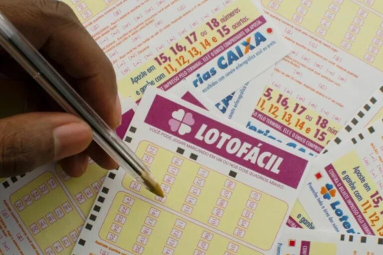 Pessoa marcando números na aposta da Lotofácil, loteria brasileira, com vários bilhetes de apostas ao redor.