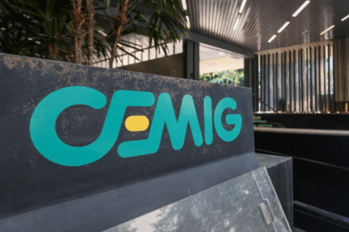 Placa com o logotipo da CEMIG na frente de uma instalação moderna de energia, destacando a marca de fornecimento de energia elétrica no Brasil.