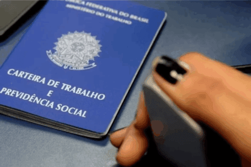 Pessoa colocando a biometria próximo à carteira de trabalho e previdência social no buffet de fotos, com foco na carteira azul do documento oficial.