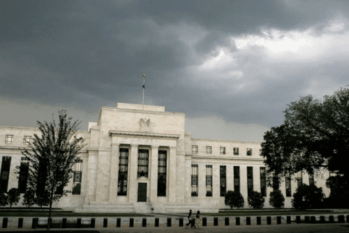 Prédio da sede do Federal Reserve em Washington, D.C., sob céu nublado e escuro.