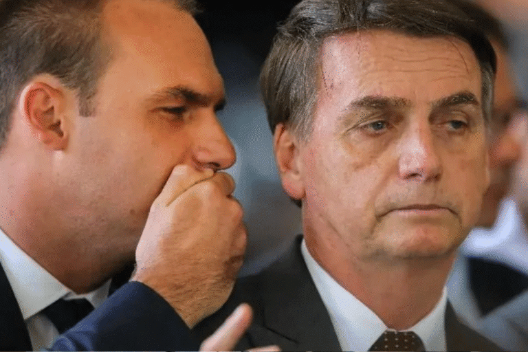 Imagem de Jair Bolsonaro e Flávio Bolsonaro em uma reunião importante, uma delas sussurrando ao ouvido da outra, dando a entender um momento de confidência ou estratégia.