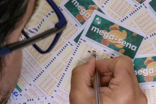 Pessoa marcando números de apostas na loteria Mega-Sena com uma caneta, cercada por múltiplos bilhetes de loteria.