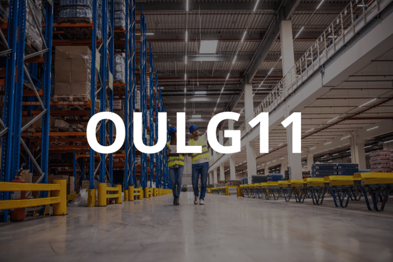 Funcionários de uma fábrica ou centro de distribuição caminhando pelo armazém com estantes cheias de produtos ao fundo, representando logística eficiente.