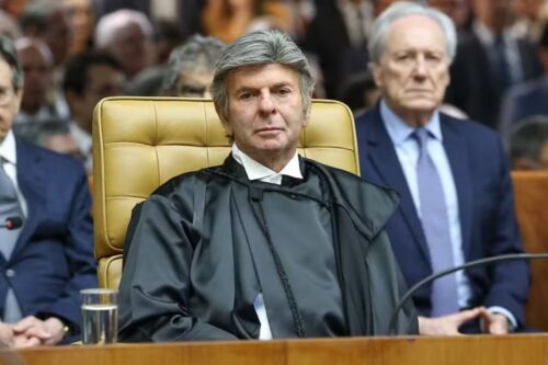 Fux em uniforme preto, sentado em uma corte, com expressão séria, durante um julgamento importante no Brasil.