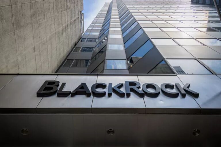 Imagem de um edifício moderno com uma fachada de vidro que reflete o céu, com a placa BlackRock na entrada, representando uma grande empresa de investimentos.