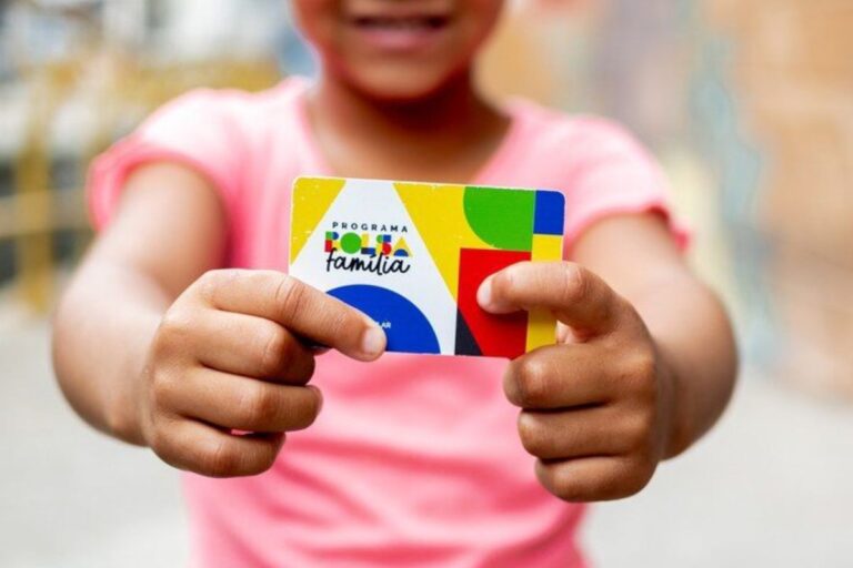 Criança segurando cartão do programa Bolsa Família