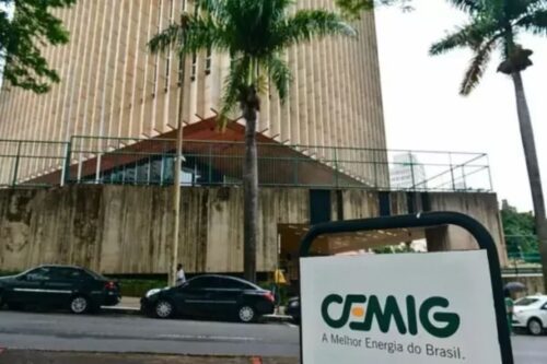 Edifício da Cemig com sua fachada moderna e destaque para o outdoor da empresa, situada em uma área urbana com árvores e carros na rua.