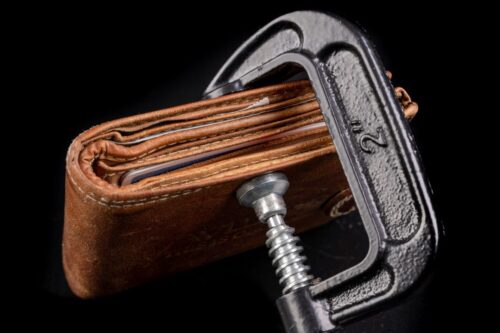 Carteira de couro velha presa em uma presilha de vantagem de origem metálica, símbolo de finanças e economia.