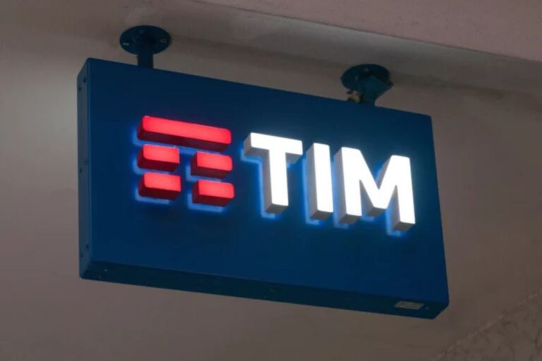 Placa de sinalização iluminada da TIM, empresa de telecomunicações, com logotipo azul, branco e vermelho, instalada em estabelecimento comercial.
