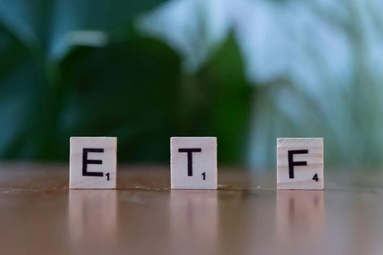 Imagem de blocos de palavras formando a sigla ETF, destacando-se as letras E, T e F em um fundo desfocado com ambiente natural ao fundo.