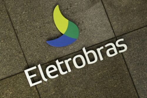 Logotipo da Eletrobras, companhia brasileira de energia, exibido no chão com letras brancas e símbolo de cores verdes e azuis, representando energia e sustentabilidade.