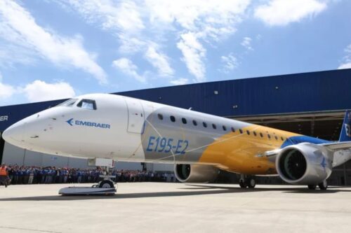 Informações sobre o novo avião Embraer E195-E2 em destaque no aeroporto com uma grande multidão observando a apresentação da aeronave.