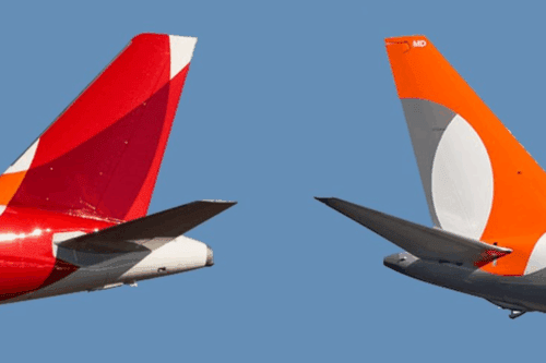 Duas aeronaves de companhias aéreas diferentes voando próximas uma da outra com caudas visíveis contra céu azul claro - imagem de aviação comercial.