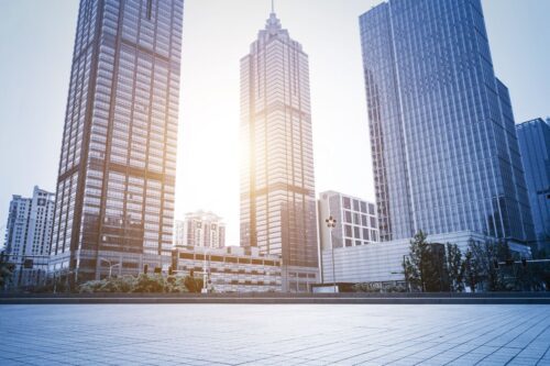 Vertiginosos arranha-céus em uma área urbana moderna ao pôr do sol, com destaque para edifícios de vidro
