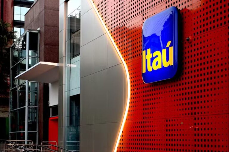 Edifício moderno com fachada de vidro e sinalização do banco Itaú em destaque na rua, com iluminação atraente e arquitetura contemporânea.