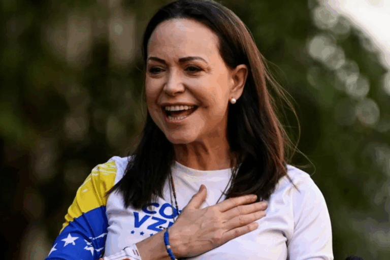Maria Corina, vencedora do Nobel da paz, sorridente em movimento ao ar livre, usando camiseta branca com detalhes em azul e amarelo, com uma expressão de alegria e entusiasmo.
