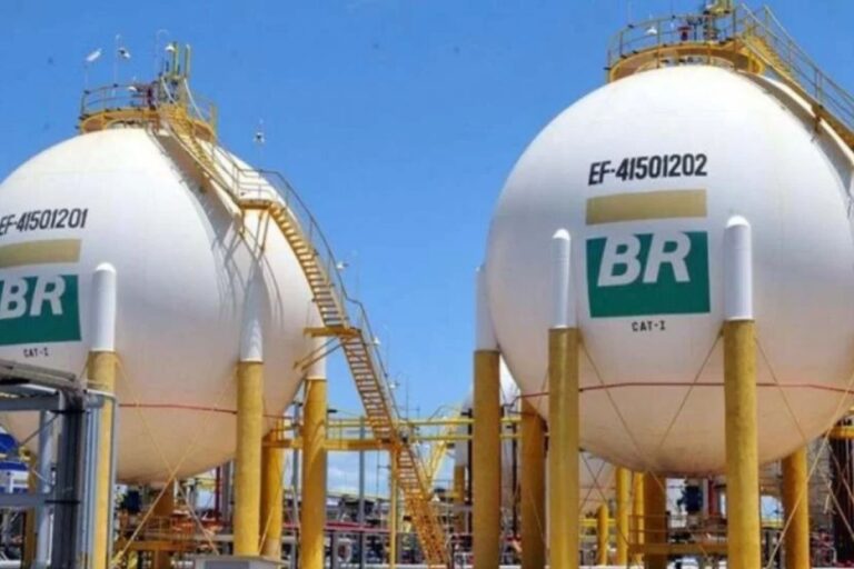 Tanques de armazenamento de petróleo da Petrobras no Brasil, com estrutura metálica amarela, sob céu azul claro.