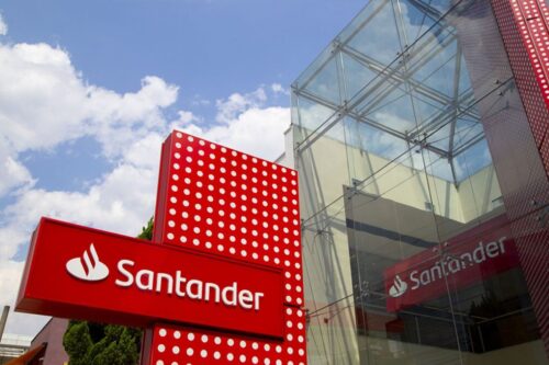 Fachada moderna de um prédio com o logotipo do banco Santander em destaque. Estrutura de vidro e design contemporâneo.