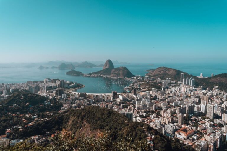 Visualização panorâmica da cidade do Rio de Janeiro com o Pão de Açúcar ao fundo e praias famosas, destacando a beleza natural e urbana do Brasil.