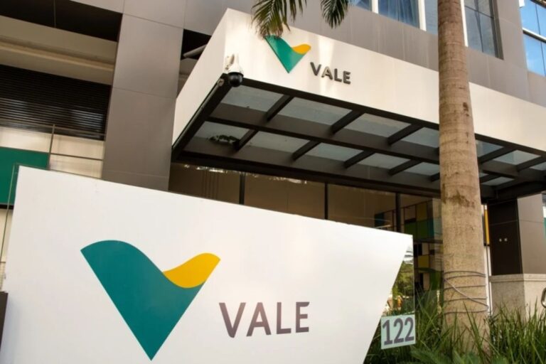Fachada de um prédio empresarial com logo da Vale, empresa de mineração, e uma placa grande com o nome Vale ao lado de uma palmeira
