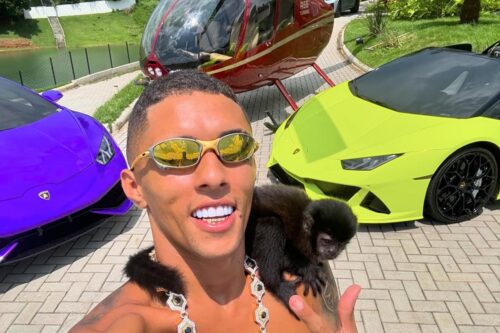 Foto do influenciador Buzeira, nome artístico de Bruno Alexssander Souza Silva, posando ao lado de carros de luxo
