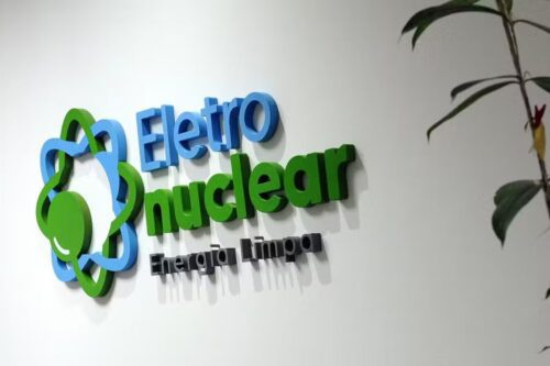 Logo da Eletronuclear da ELET3 com os dizeres “Energia Limpa” em parede branca, simbolizando o setor nuclear de energia no Brasil.