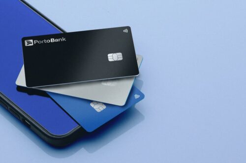 Cartões Porto Bank Visa Infinite Privilege em diferentes cores sobre smartphone, simbolizando exclusividade e alta renda.