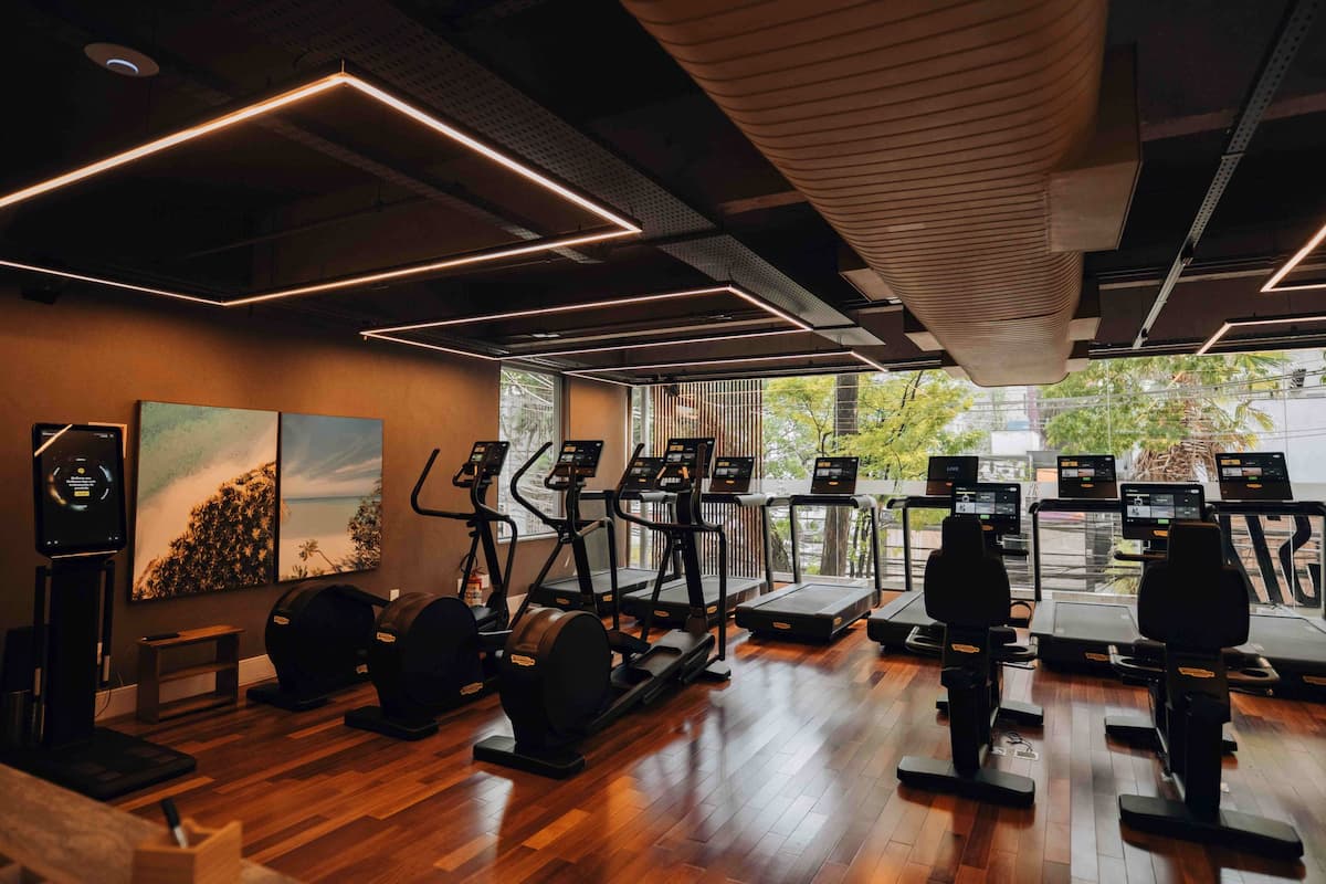 Sala de treinos moderna da SIX Sport Life com esteiras, bicicletas e design sofisticado em madeira.