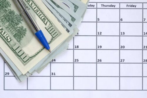 Planejamento financeiro usando calendário, dinheiro em notas de dólar e caneta