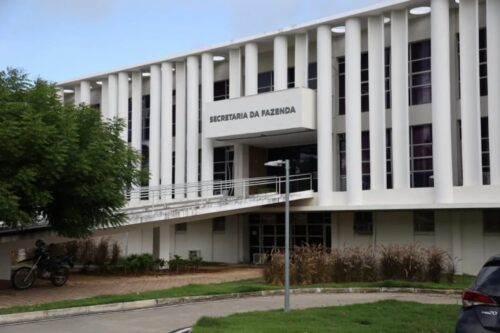 Fachada da Secretaria da Fazenda do RN, prédio público moderno com colunas brancas, relacionado ao Edital Sefaz RN.