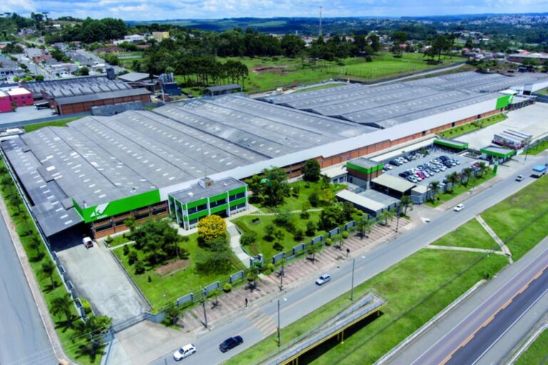 Vista aérea de uma unidade industrial da Klabin com galpões, áreas verdes e acesso viário ao redor.