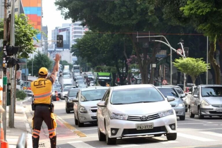 Placas de trânsito e carros em avenida movimentada após anúncio de que o rodízio de carros é suspenso em São Paulo.